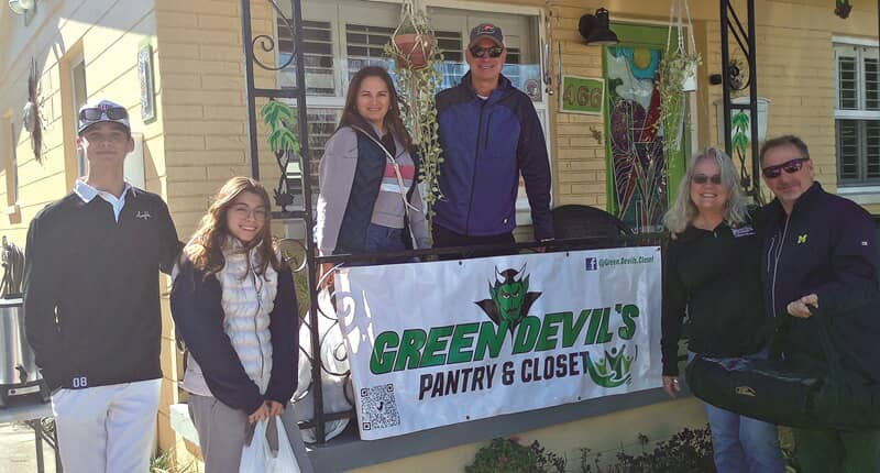 An image of people gathered around a Green Devil's Pantry & Closet sign.
